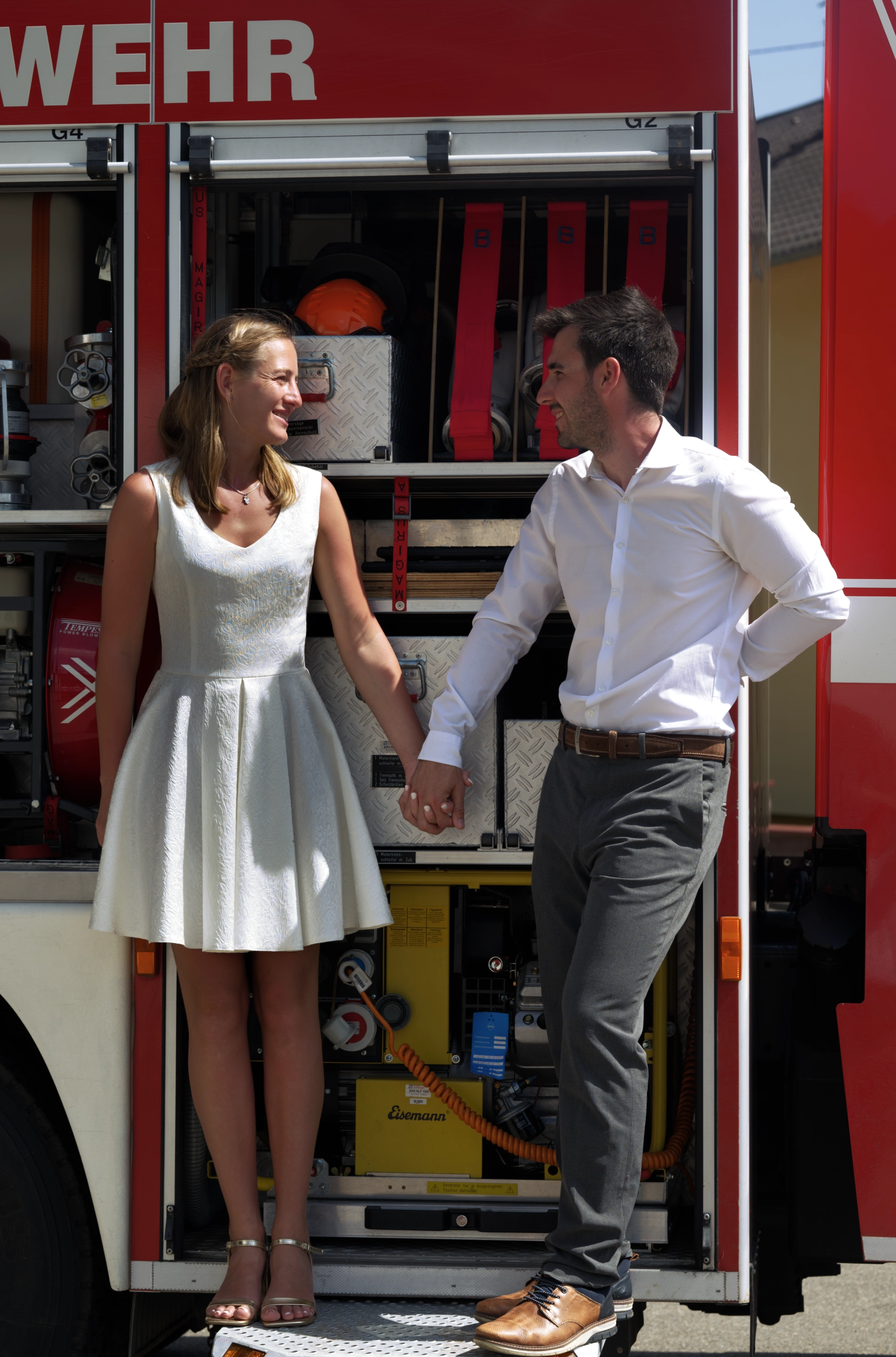 Scarlett und David sitzen vor dem Feuerwehrfahrzeug
